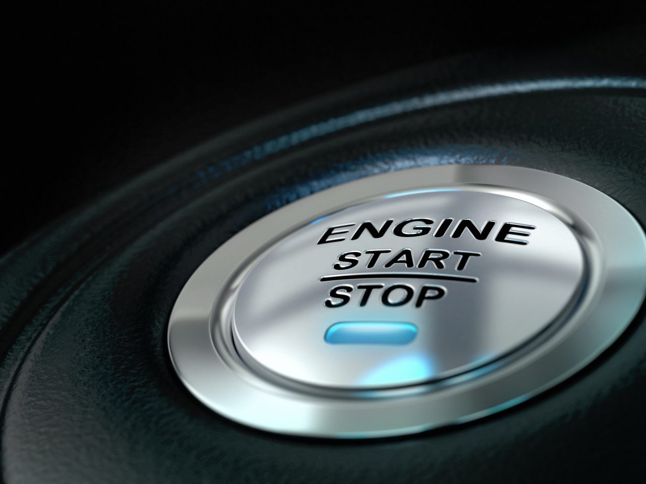 Car engine start and stop button with blue light anf black textured background, close up and details on the text